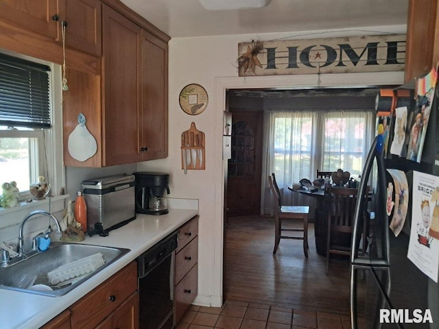 kitchen featuring dark tile patterned floors, dishwasher, sink, and a wealth of natural light