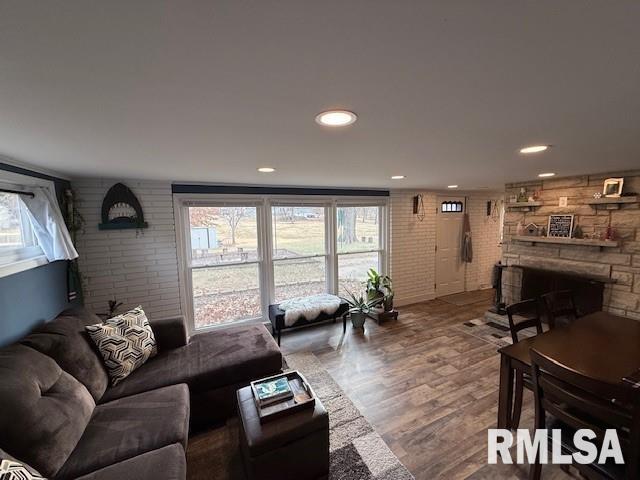 living room with wood-type flooring, brick wall, and a fireplace