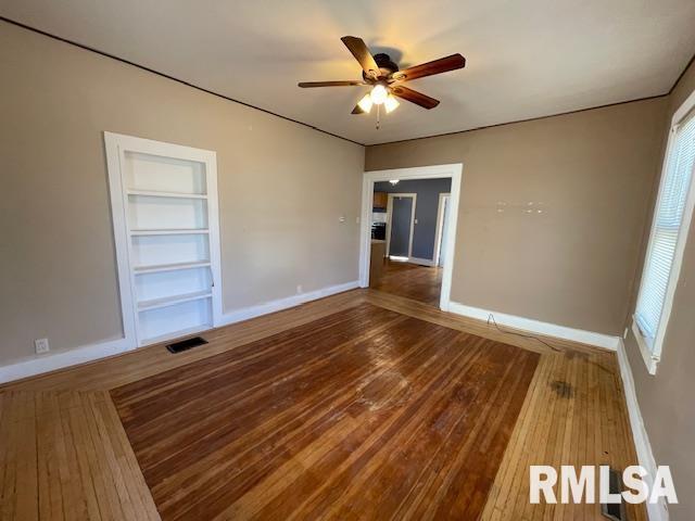 unfurnished room featuring hardwood / wood-style flooring, ceiling fan, and built in shelves