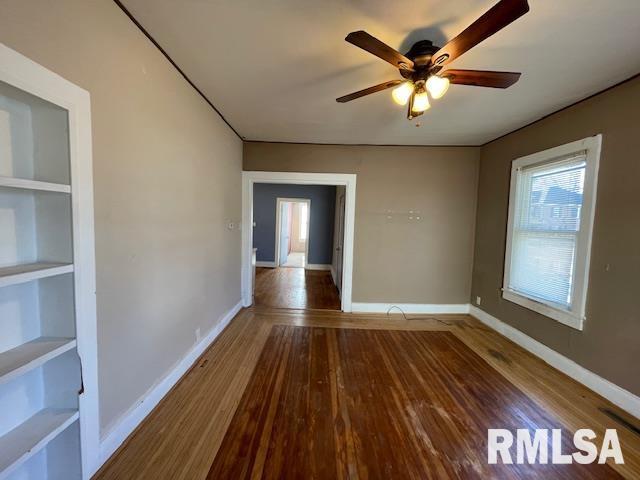 spare room with built in shelves, ceiling fan, and hardwood / wood-style floors