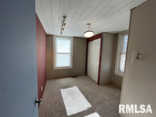 unfurnished bedroom featuring light colored carpet and rail lighting