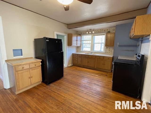 kitchen featuring sink, stove, backsplash, light hardwood / wood-style floors, and black fridge