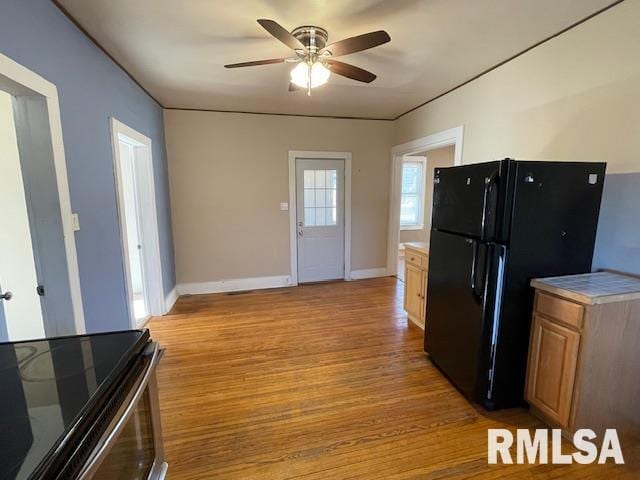 kitchen with black refrigerator, light hardwood / wood-style floors, stainless steel range with electric stovetop, and ceiling fan