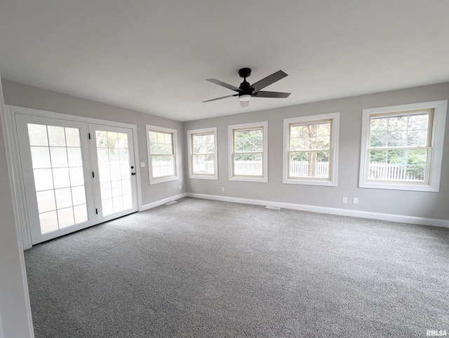 carpeted spare room featuring ceiling fan, visible vents, and baseboards