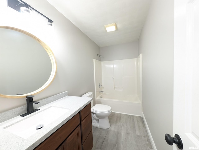 bathroom with toilet,  shower combination, wood finished floors, and vanity