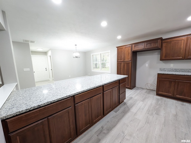 kitchen with light stone counters, recessed lighting, visible vents, light wood finished floors, and pendant lighting