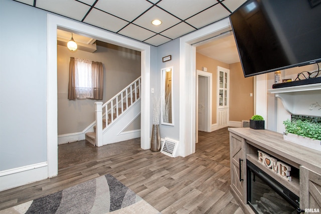 living room with a paneled ceiling and light wood-type flooring