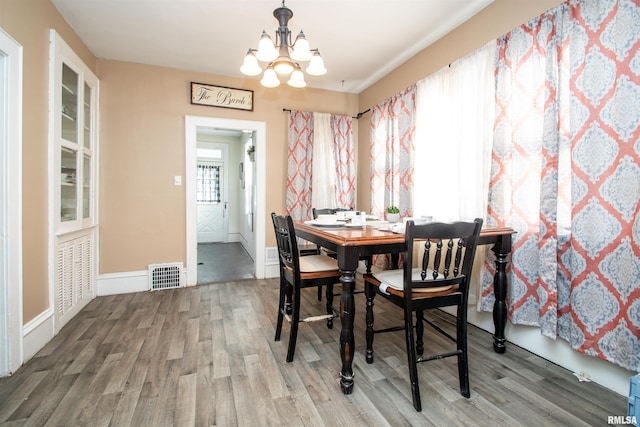 dining area with hardwood / wood-style flooring and a notable chandelier