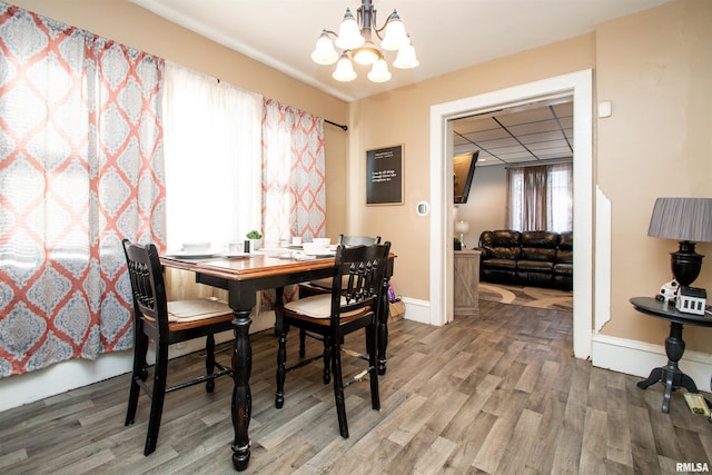 dining area featuring wood-type flooring and a notable chandelier