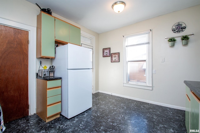 kitchen with white fridge and green cabinets