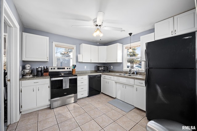 kitchen with sink, light tile patterned floors, hanging light fixtures, black appliances, and white cabinets