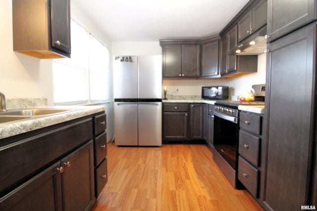 kitchen featuring dark brown cabinetry, stainless steel appliances, sink, and light hardwood / wood-style flooring