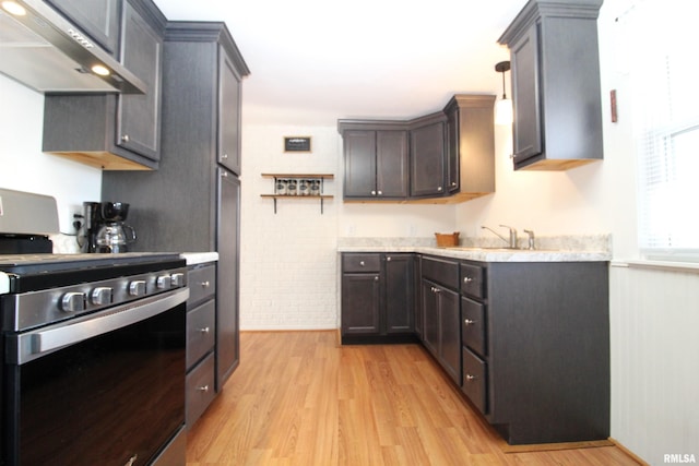 kitchen with brick wall, sink, stainless steel stove, and light hardwood / wood-style flooring