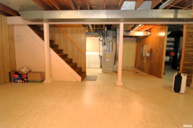 basement featuring washer / clothes dryer, hardwood / wood-style floors, heating unit, and wooden walls