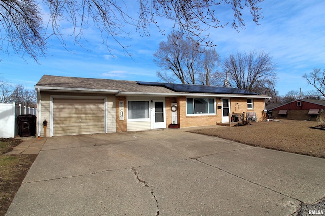 single story home with a garage and solar panels