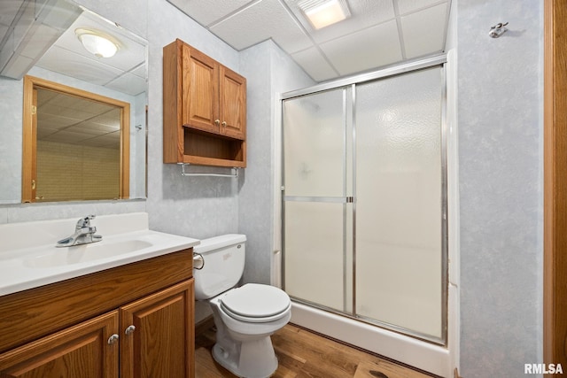 bathroom featuring a paneled ceiling, hardwood / wood-style floors, an enclosed shower, vanity, and toilet