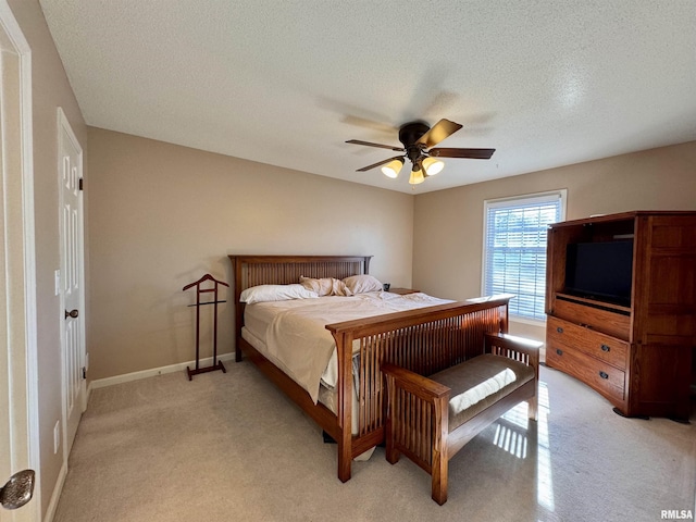 bedroom featuring a textured ceiling, light colored carpet, and ceiling fan