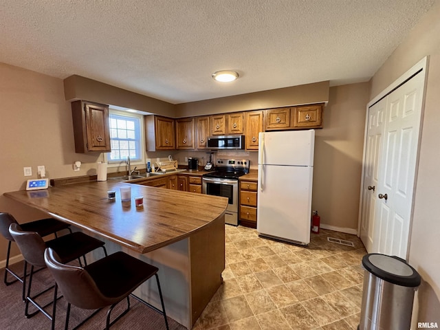 kitchen with appliances with stainless steel finishes, sink, a breakfast bar area, and kitchen peninsula