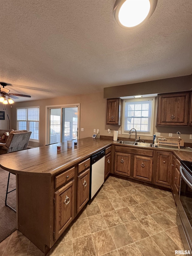 kitchen featuring sink, ceiling fan, appliances with stainless steel finishes, a textured ceiling, and kitchen peninsula