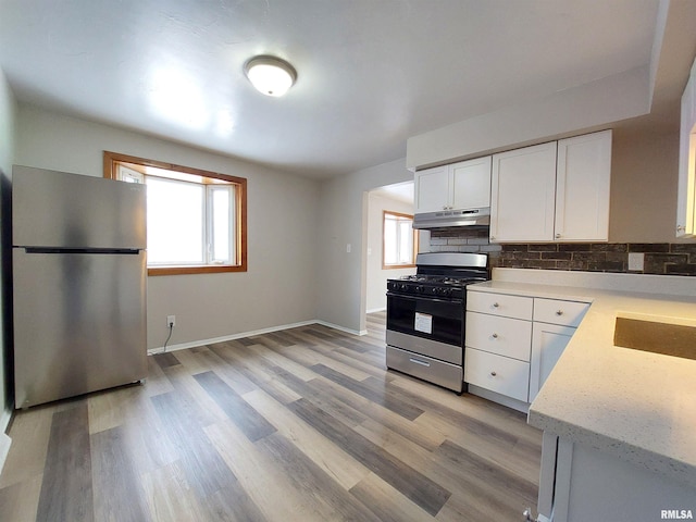 kitchen with white cabinetry, tasteful backsplash, light wood-type flooring, stainless steel refrigerator, and gas range oven