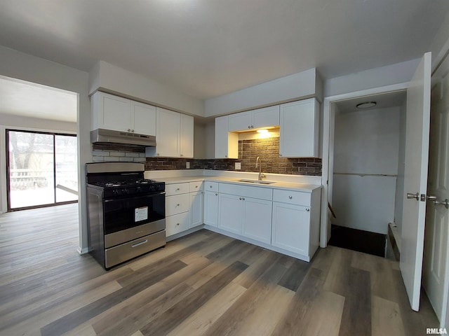 kitchen with stainless steel gas stove, sink, decorative backsplash, and white cabinets