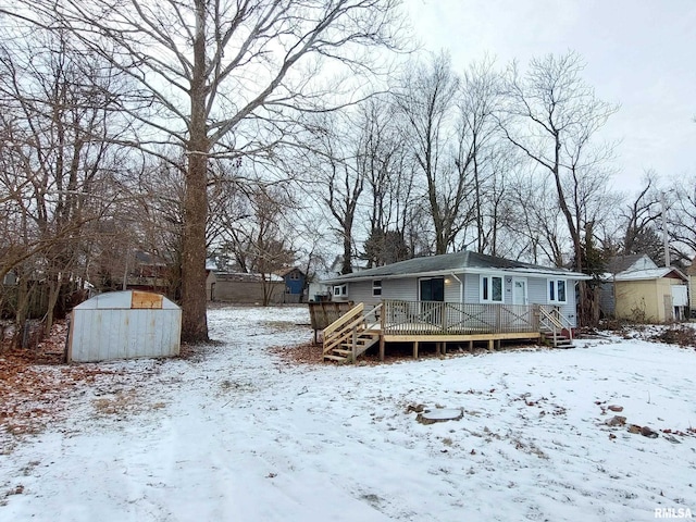 snow covered property featuring a deck and a storage unit