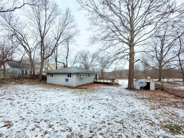 snow covered property featuring a deck and a shed