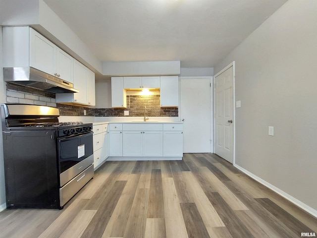 kitchen featuring tasteful backsplash, sink, white cabinets, gas range oven, and light hardwood / wood-style flooring