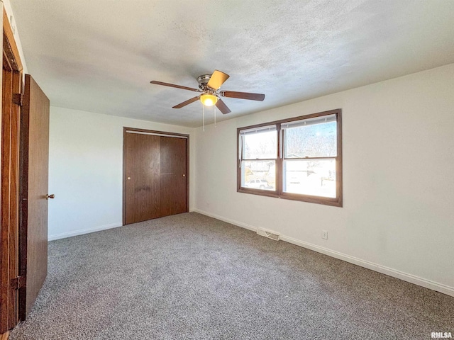 unfurnished bedroom featuring a textured ceiling, visible vents, baseboards, a closet, and carpet