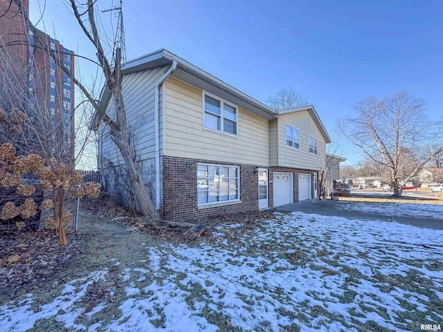 snow covered back of property with a garage