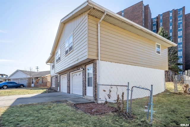 view of side of home featuring driveway, an attached garage, fence, and a yard