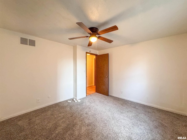 unfurnished room featuring carpet floors, visible vents, ceiling fan, and baseboards