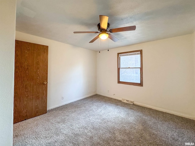 empty room featuring a ceiling fan, baseboards, visible vents, and carpet flooring