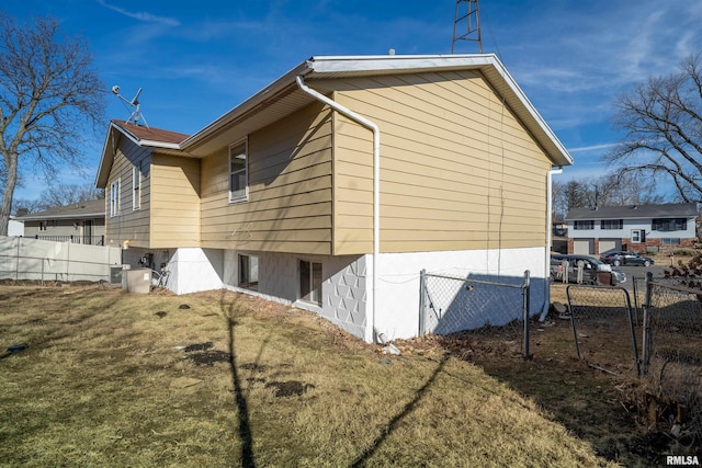 view of home's exterior with fence, central AC unit, and a lawn