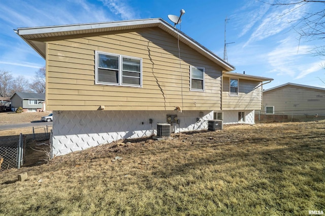 back of property with a lawn, cooling unit, and fence