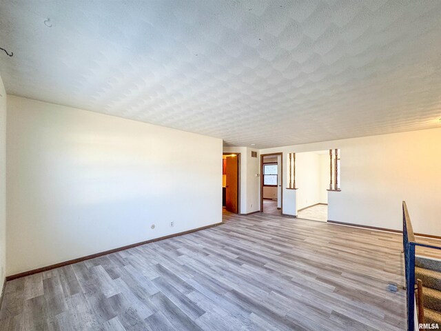 empty room featuring a textured ceiling and light hardwood / wood-style flooring