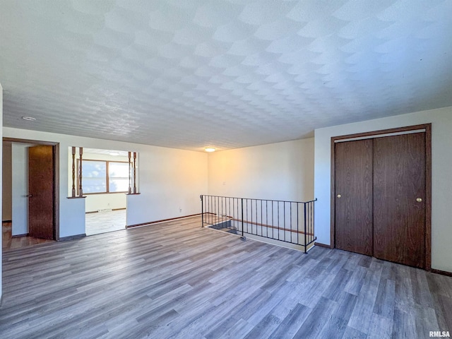 unfurnished room featuring a textured ceiling, baseboards, and wood finished floors