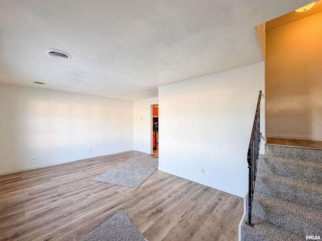 spare room featuring stairs, light wood-style flooring, visible vents, and baseboards