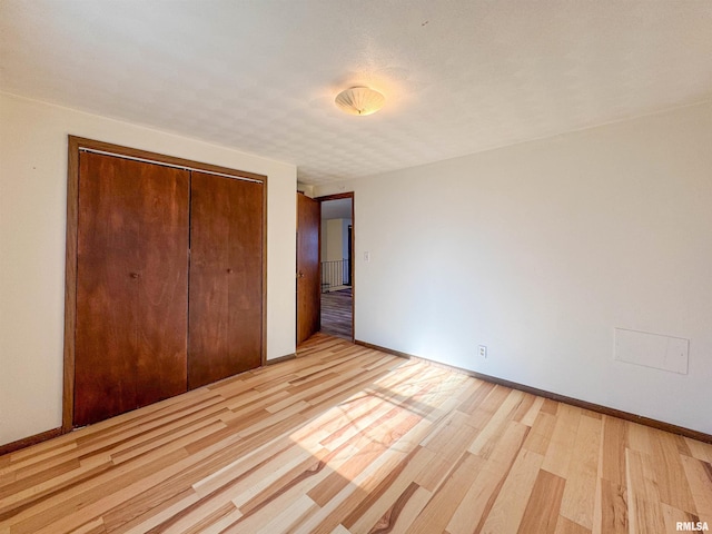 unfurnished bedroom with a closet and light wood-type flooring