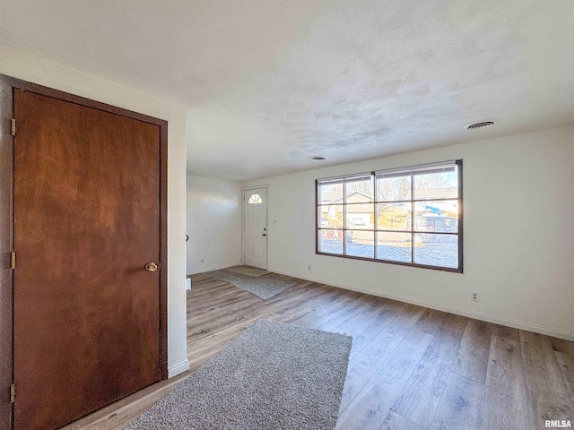 interior space featuring baseboards, visible vents, and light wood finished floors