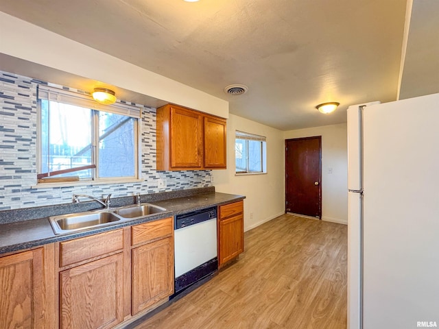 kitchen featuring white appliances, visible vents, dark countertops, a sink, and backsplash