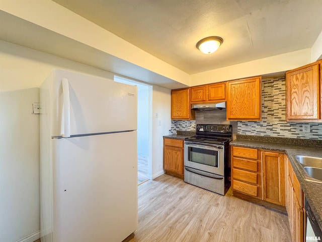 kitchen featuring stainless steel appliances, sink, light wood-type flooring, and backsplash