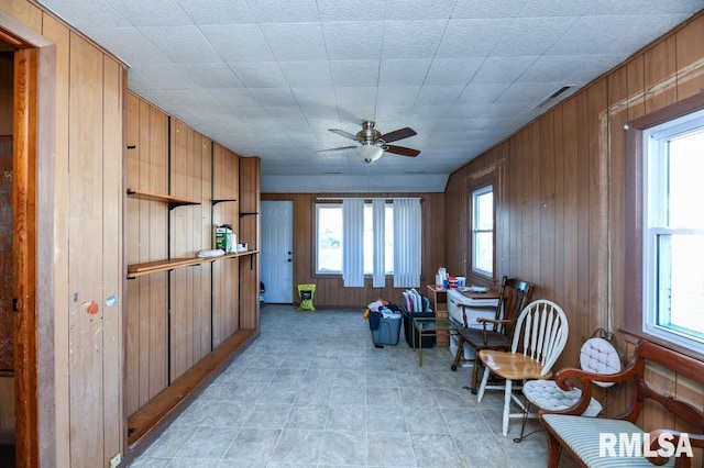 sitting room featuring ceiling fan and wooden walls