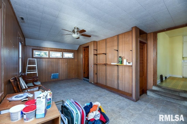 interior space featuring ceiling fan and wood walls