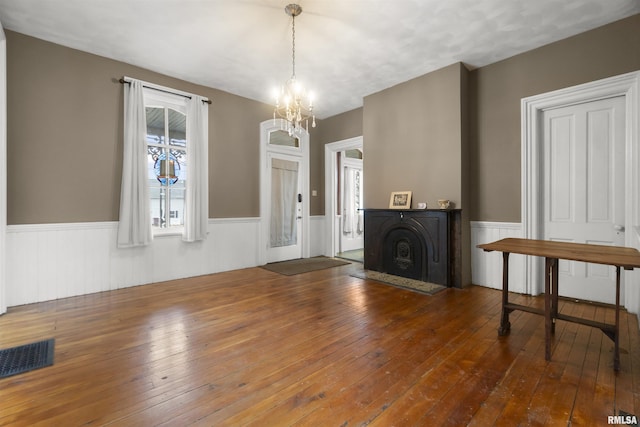 unfurnished living room with hardwood / wood-style floors, a notable chandelier, and a fireplace