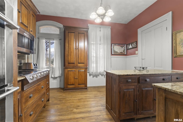 kitchen with pendant lighting, dark hardwood / wood-style flooring, a notable chandelier, stainless steel appliances, and light stone countertops