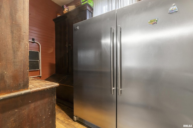 kitchen with light wood-type flooring, high end refrigerator, and wooden walls