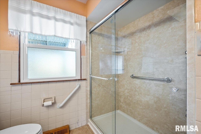 bathroom featuring tile walls, a shower with door, and toilet