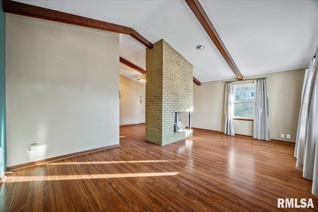 unfurnished living room with a fireplace, lofted ceiling with beams, and hardwood / wood-style floors