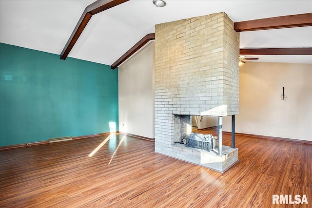 unfurnished living room featuring lofted ceiling with beams, a brick fireplace, and light wood-type flooring